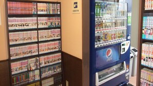Màquina expenedora amb el logotip de Pepsi i una estant plena de llibres de manga.