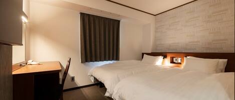A hotel room with two beds, a desk, a chair, a window with curtains, and a wall with a patterned design.