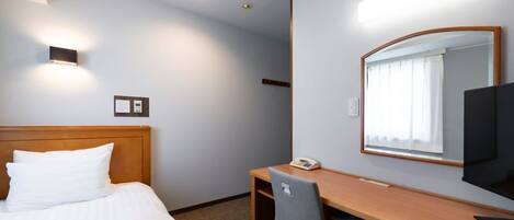 Una habitación de hotel con cama, escritorio, silla, teléfono, televisión y espejo.