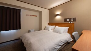 Una habitació d'hotel amb un llit gran, un escriptori i una finestra amb cortines.