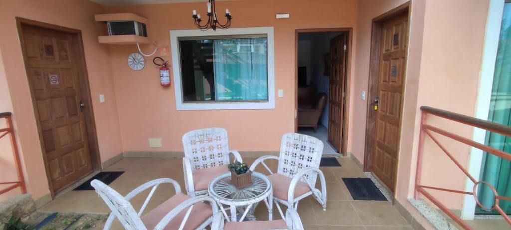 A balcony with a table and chairs, a fire extinguisher, and a window.