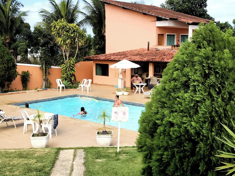 A swimming pool area with lounge chairs, a table, and a building in the background.