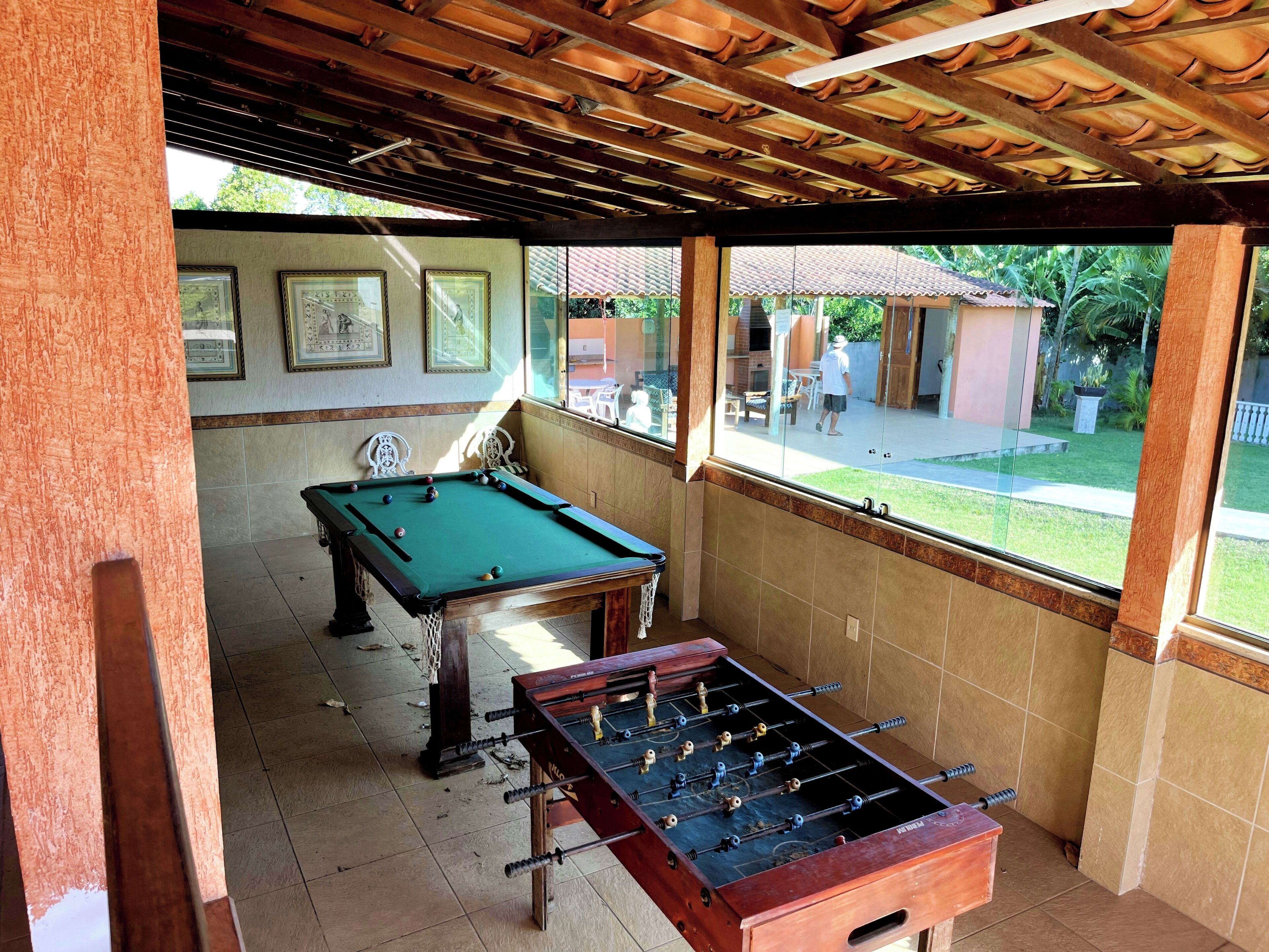 A pool table and foosball table in a room with tiled walls and a wooden ceiling.