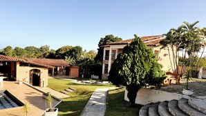 A courtyard with a swimming pool, outdoor seating, and a staircase leading to a building with a tiled roof.