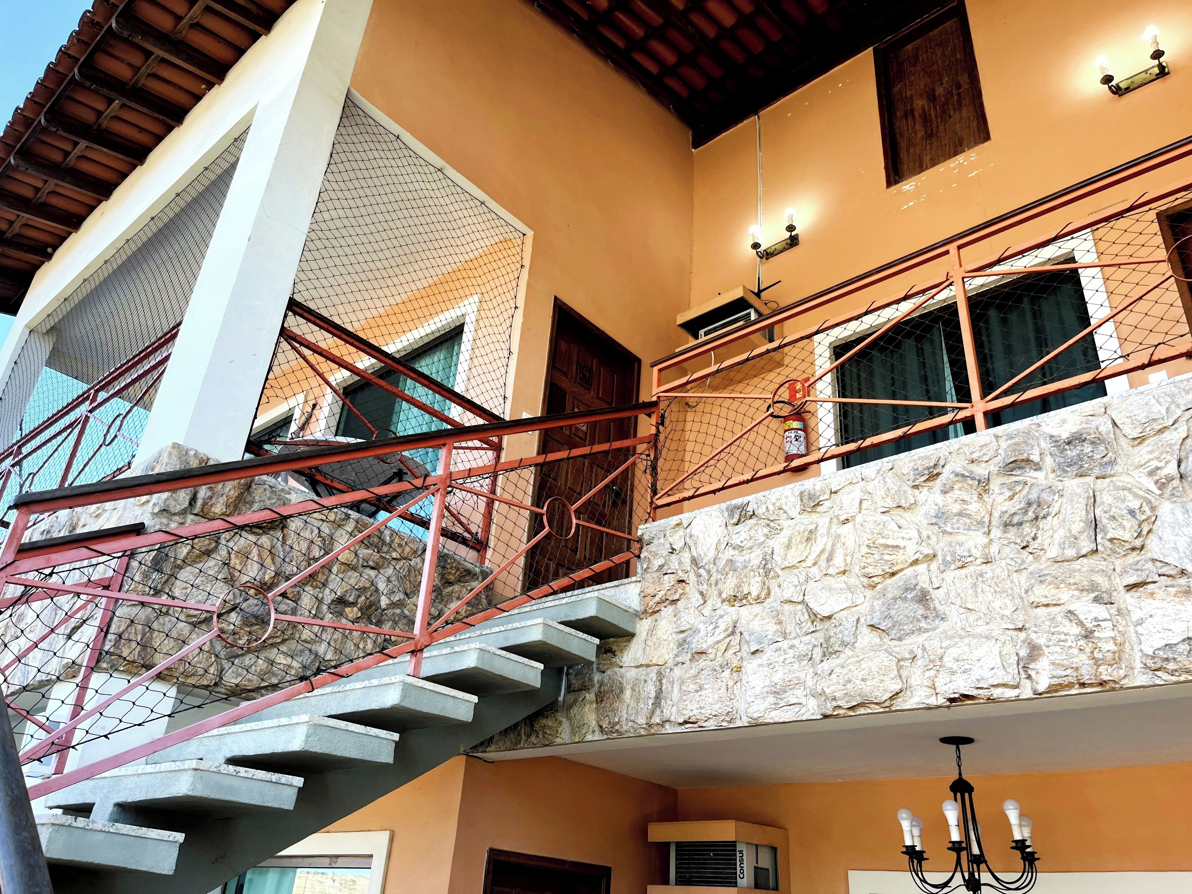 A multi-level building with a stone facade, a staircase with a red railing, and a chandelier.