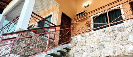 A multi-level building with a stone facade, a staircase with a red railing, and a chandelier.