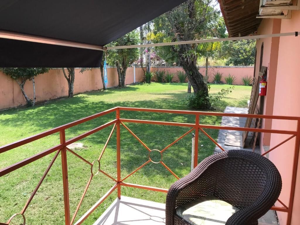 A balcony with a wicker chair, a metal railing, and a view of a well-maintained lawn and trees.