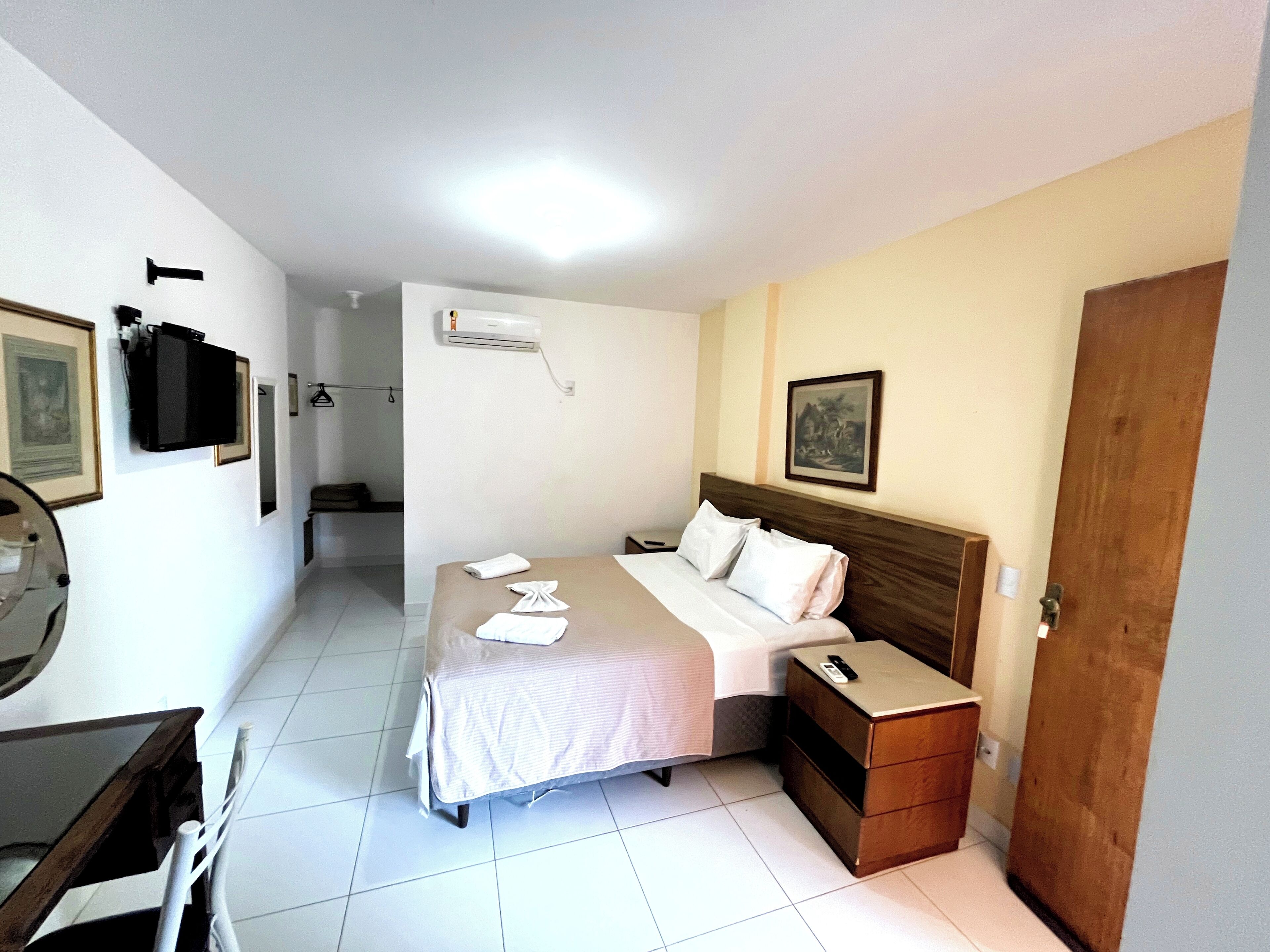 Ein Hotelzimmer mit Bett, Nachttisch und Spiegel.