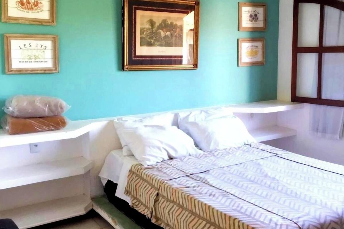 A bedroom with a bed, a nightstand, a window, and a ceiling fan.
