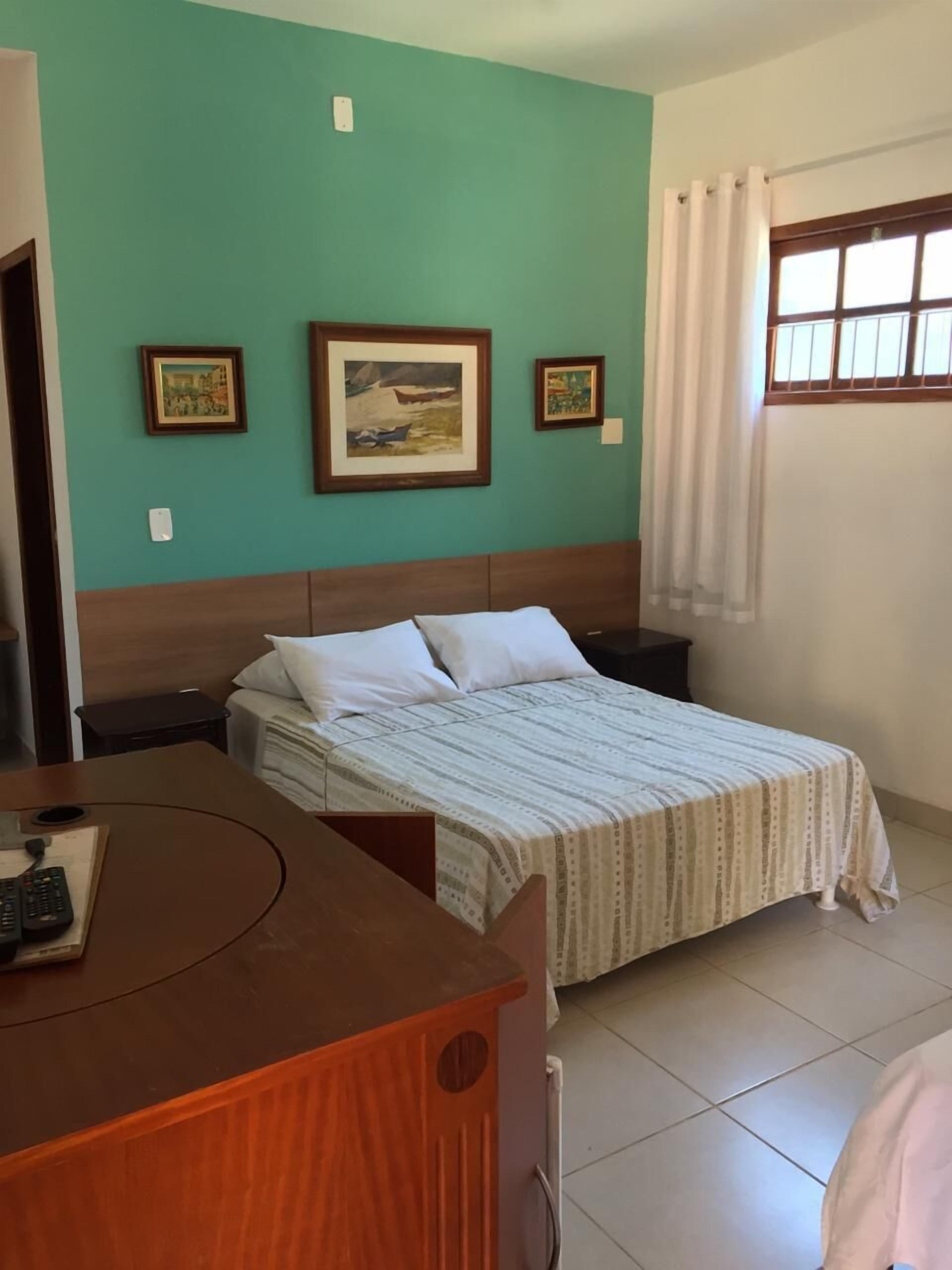 A hotel room with a bed, a desk with a telephone, and a window with curtains.