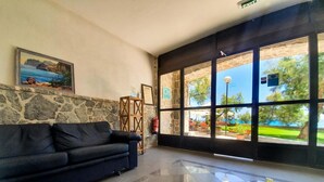 Eine Lobby mit einer Steinwand, einem schwarzen Sofa, einem hölzernen Tischchen und einem großen Fenster mit Blick ins Freie.