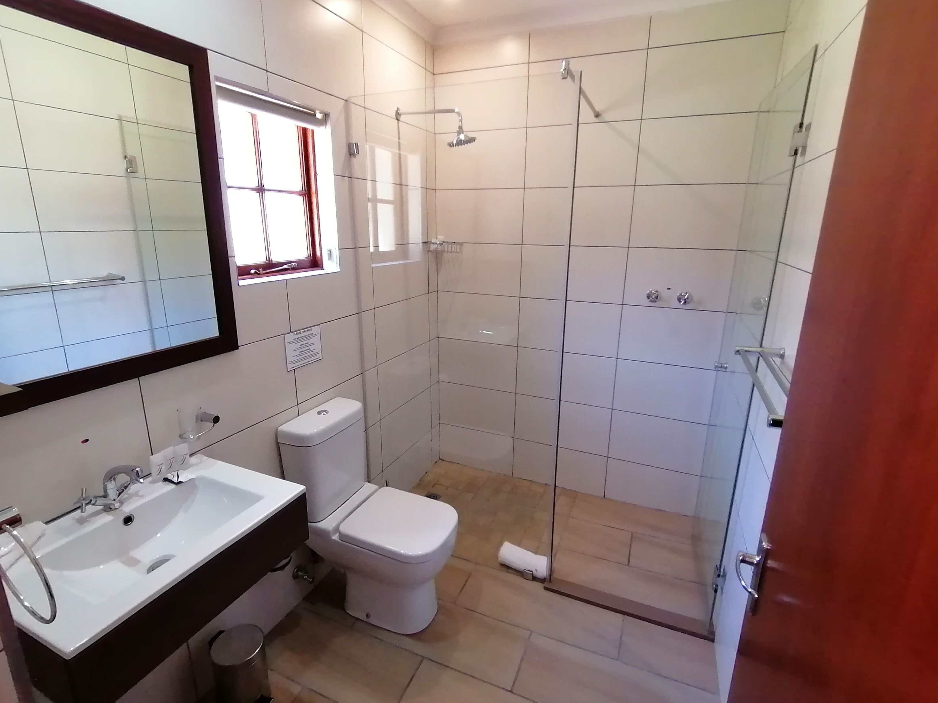 A bathroom with a white sink, toilet, and glass-enclosed shower.