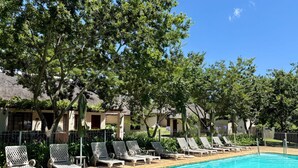 A poolside area with lounge chairs and a clear blue pool. - Eight Bells Mountain Inn (Ruiterbos)