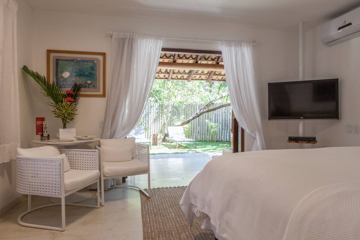 Ein Hotelzimmer mit Bett, Fernseher, Schreibtisch und Stuhl sowie Blick ins Freie.