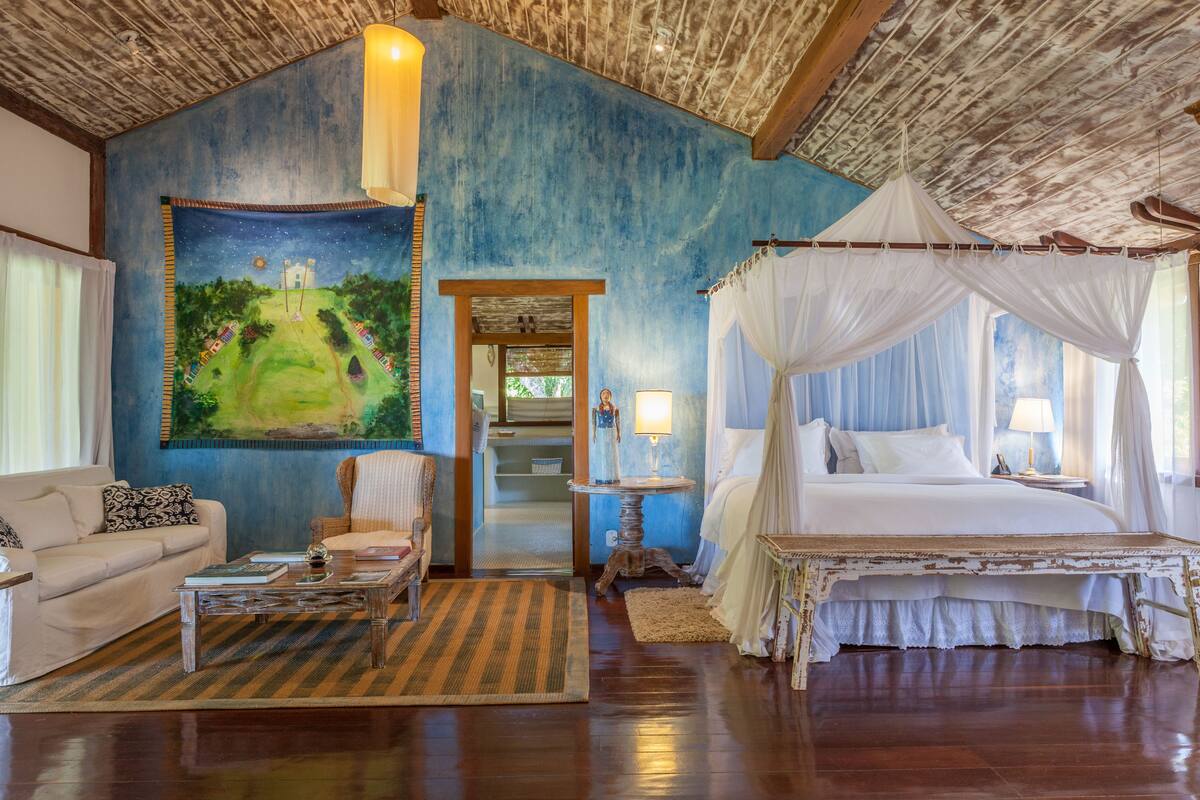 Ein Schlafzimmer mit Himmelsbett, Wandgemälde mit Sternenhimmel und Blick ins Freie.