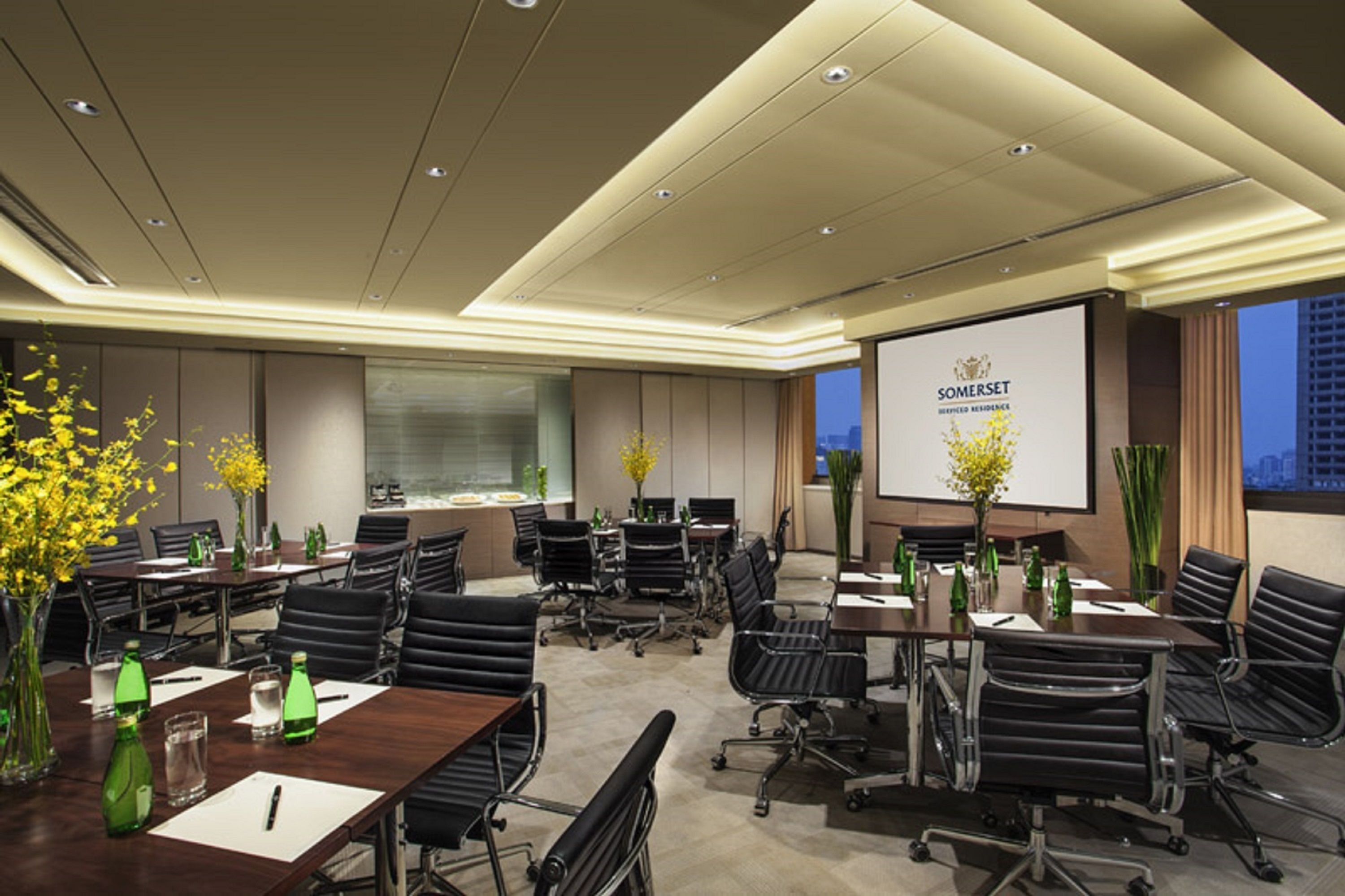 A conference room with multiple tables, chairs, and a presentation screen displaying 'Somerset'.