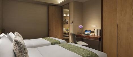 A hotel room with two beds, a desk with a computer, and a chair.
