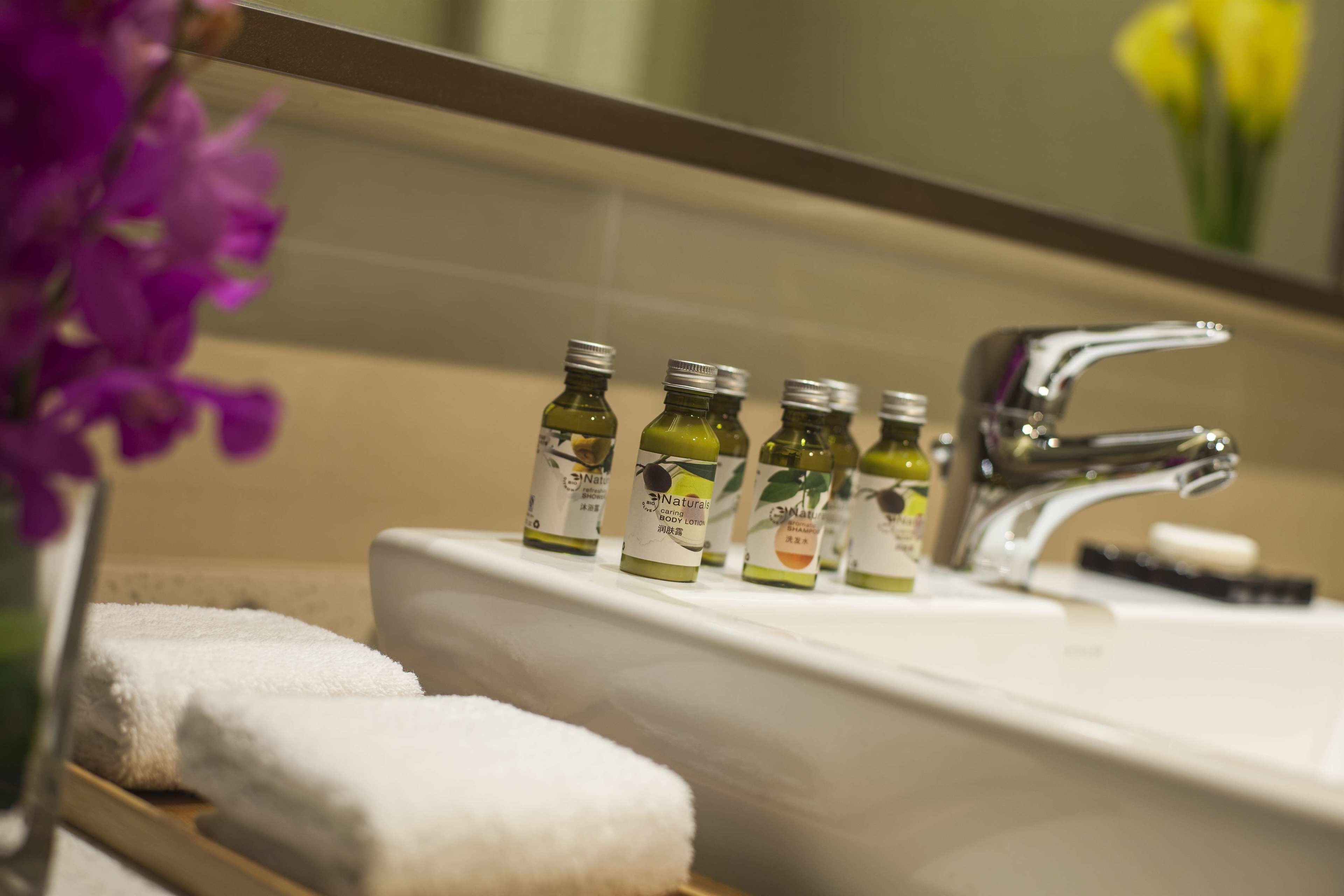 Un baño con un lavamanos, varias botellas de crema corporal y un espejo.