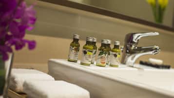 A bathroom with a sink, several bottles of body lotion, and a mirror.