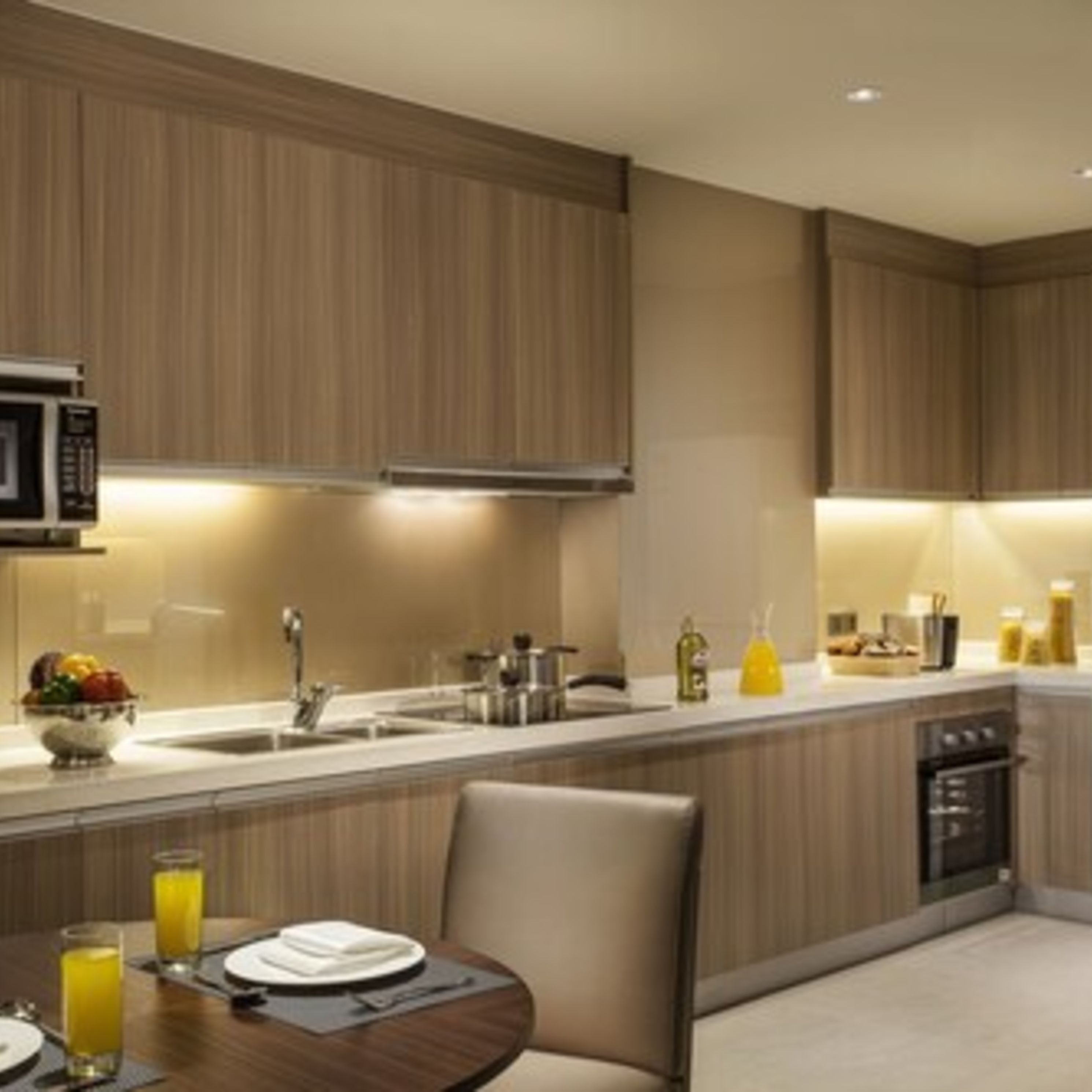 A modern kitchen with wooden cabinets, a microwave, a sink, and a dining area with a table set for two.