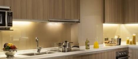 A modern kitchen with wooden cabinets, a microwave, a sink, and a dining area with a table set for two.