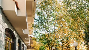 A covered walkway with a metal railing, leading to a building with a stone facade and arched doorways. - Olympia Hotel (Yerevan)