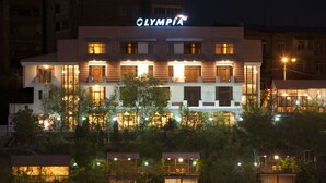 A multi-story hotel with a prominent "OLYMPIA" sign, multiple balconies, and well-lit windows. - Olympia Hotel (Yerevan)