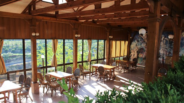 A wooden interior with tables and chairs, large windows, and a mural on the wall. - Olympia Hotel (Yerevan)