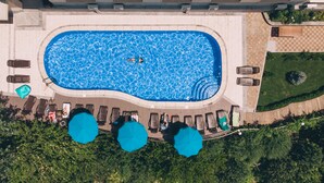 An aerial view of a swimming pool with lounge chairs and umbrellas, surrounded by greenery. - Olympia Hotel (Yerevan)
