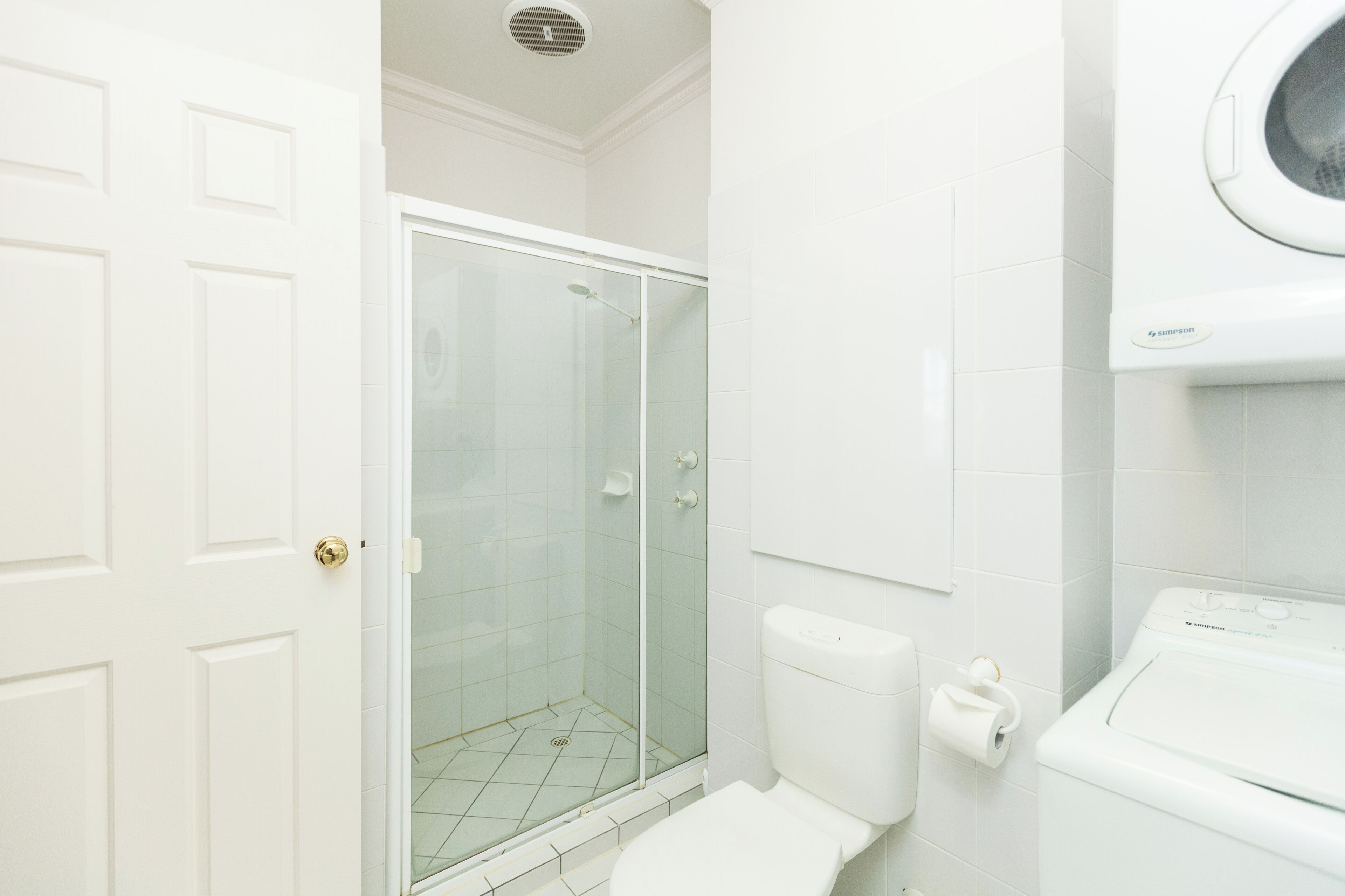 Un baño con ducha de vidrio, inodoro y lavadora.