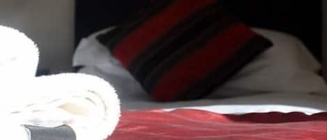 A bed with a red blanket and a pillow with a striped pattern.
