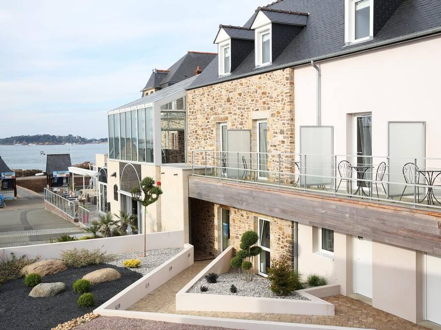 Een modern gebouw met een gevel van steen, grote ramen en een balkon met buitenmeubilair.
