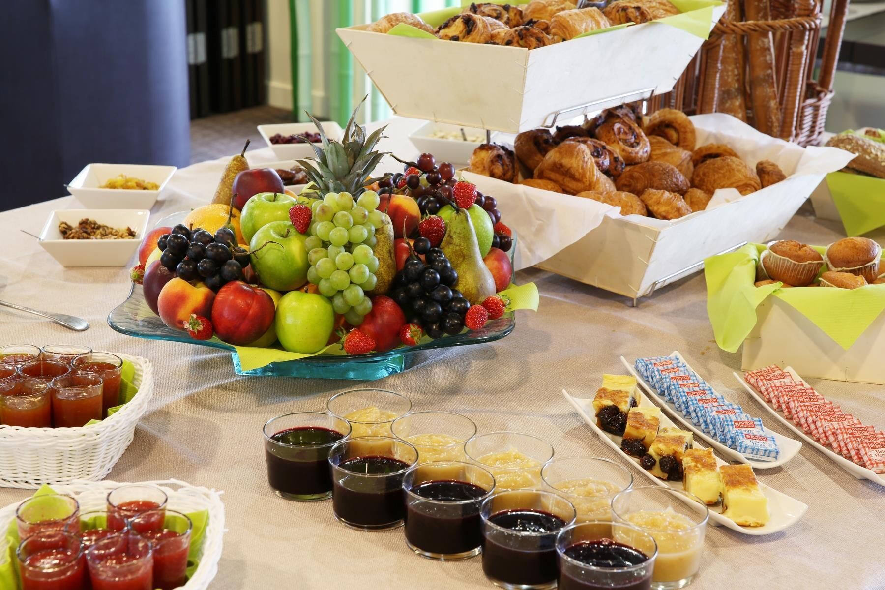 A buffet table with various food items including fruits, pastries, and condiments.