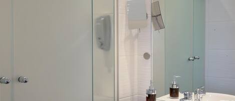 A modern bathroom with a glass shower enclosure, a white sink with a mirror, and a towel rack.