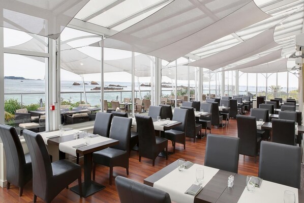 Un restaurante con terraza al aire libre y vistas al mar.