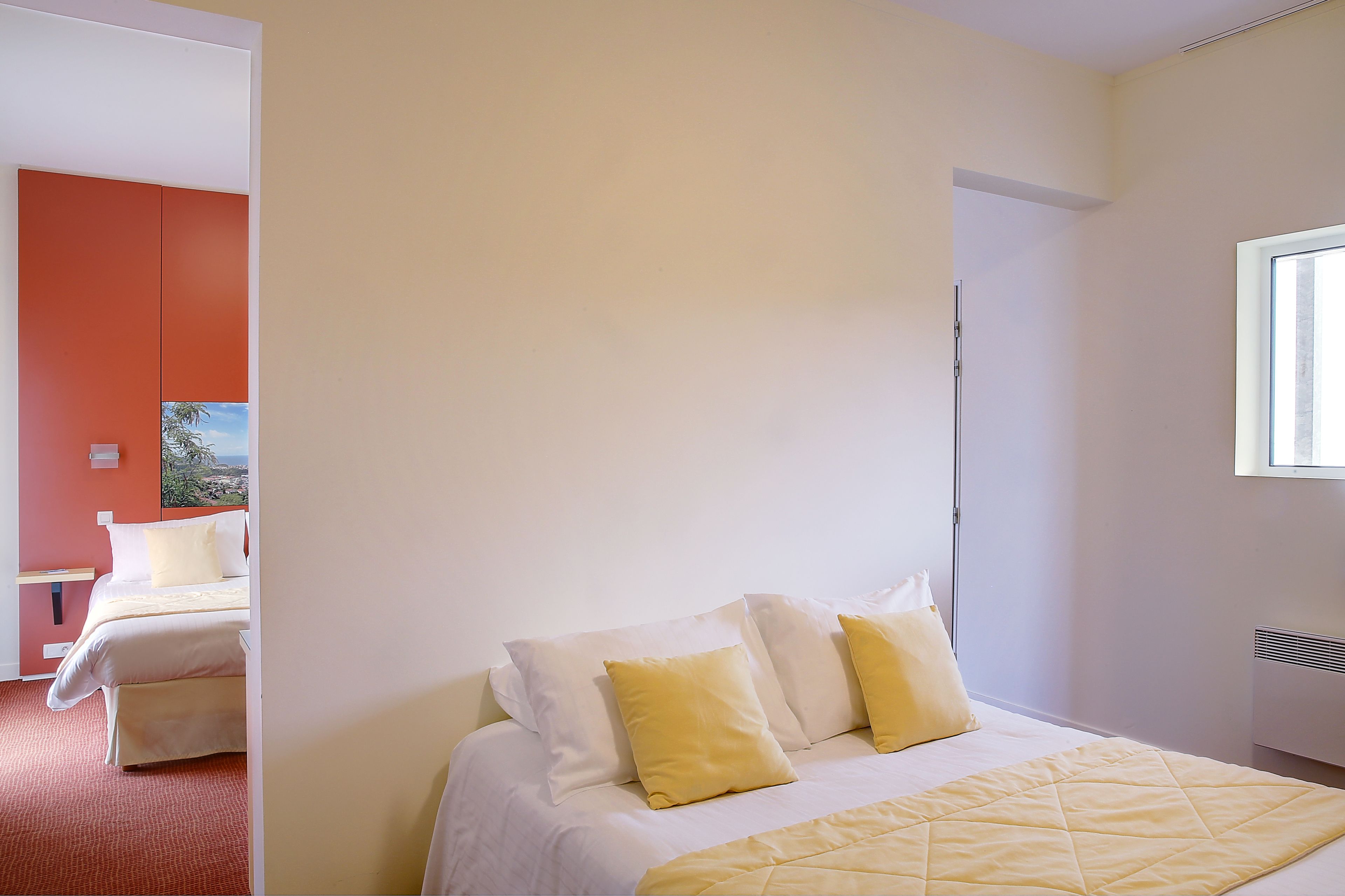 A hotel room with a bed, a window, and a view of the outdoors.