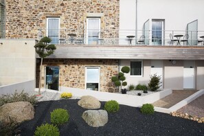 Un edificio de piedra con balcón, mobiliario exterior y jardín ajardinado.