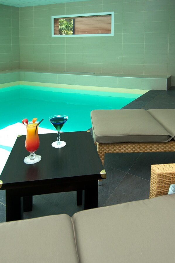 Zona de piscina con mesa y sillones de descanso.