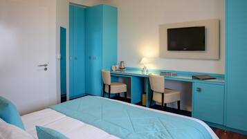 Une chambre d’hôtel comprenant un lit, un bureau avec deux chaises, un téléviseur fixé au mur et une armoire.
