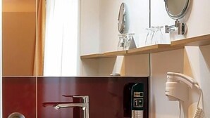 A bathroom with a large mirror, a sink, a towel, and a hairdryer. - Zum Hirschen (Donaueschingen)