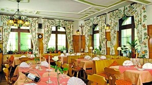 A dining area with tables set for service, a chandelier, and large windows with curtains. - Zum Hirschen (Donaueschingen)