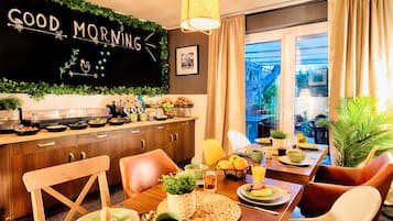 A modern kitchen with a "GOOD MORNING" sign, wooden cabinets, and a dining area with chairs and a table set for breakfast.
