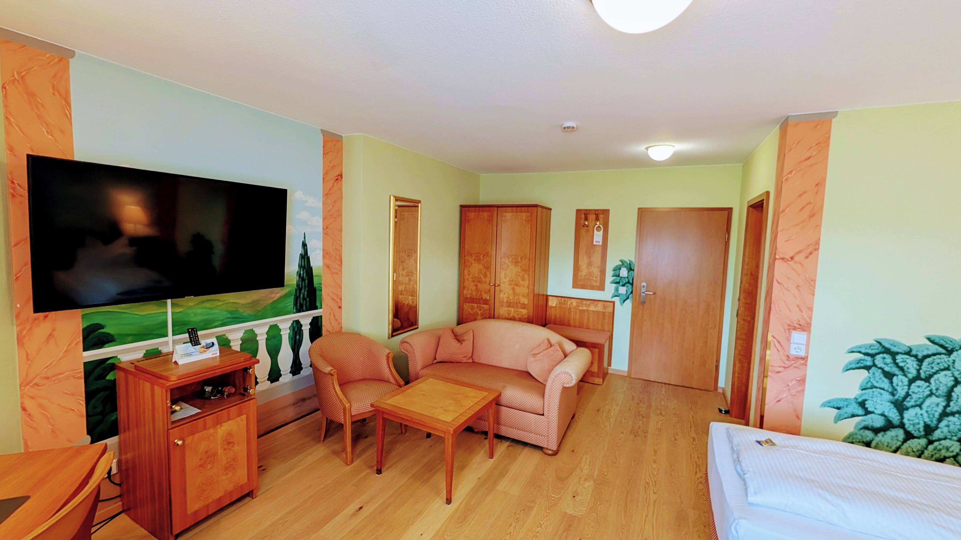 Ein Wohnzimmer mit Fernseher, Sofa, Couchtisch und einem Bett.