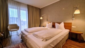 A hotel room with two beds, a chair, a nightstand, and a wall-mounted lamp. - Hotel Restaurant Felix (Bensheim)