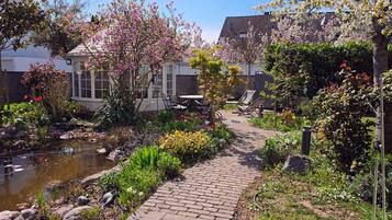 A garden with a pond, a brick pathway, and outdoor seating.