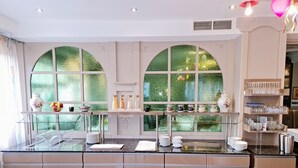 A modern kitchen with a central island, large arched windows, and a glass display case. - Hotel Restaurant Felix (Bensheim)
