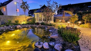 A well-lit garden with a pond, stone pathway, and a gazebo. - Hotel Restaurant Felix (Bensheim)