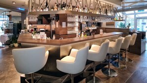 A modern bar area with a counter, bar stools, and a variety of bottles and glasses. - Hotel Restaurant Felix (Bensheim)