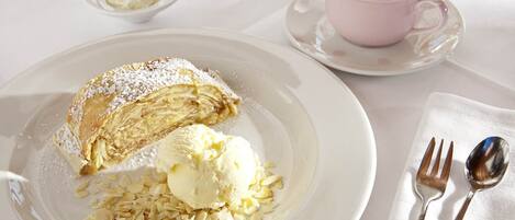 A dessert plate with a pastry and ice cream, a cup of coffee, and a small bowl of whipped cream.