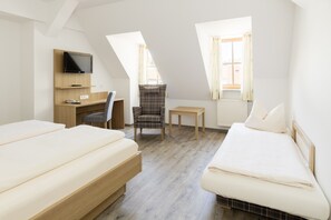 Una habitación con dos camas, un escritorio, una silla, un televisor y una ventana.
